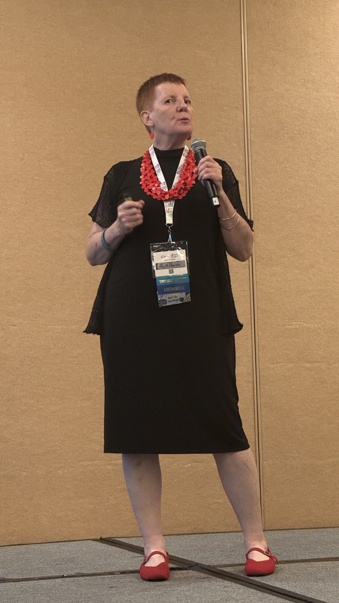 Ruth Pearce presenting on stage with a microphone